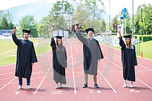 Graduation group of students celebrating on athletic track with