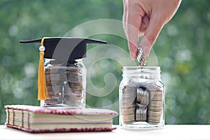 Graduation hat on coins money in the glass bottle on natural green background, Saving money for education concept