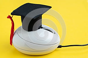 Graduation hat on computer mouse on solid yellow background using as online course, e-learning or internet study via website and