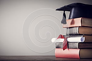 Graduation hat and diploma with book on table