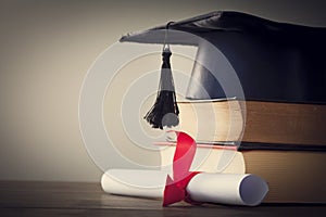 Graduation hat and diploma with book on table