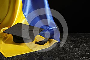 Graduation hat and flag of Ukraine on black background