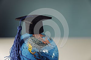 Graduation hat on globe model close-up. Education and scholarships concept