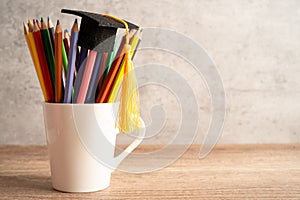 Graduation hat with pencil in cup with copy space