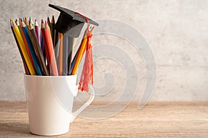 Graduation hat with pencil in cup with copy space