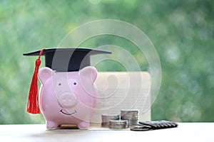 Graduation hat on piggy bank with stack of coins money on natural green background, Saving money for education concept
