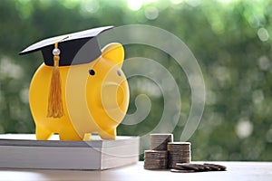 Graduation hat on piggy bank with stack of coins money on nature green background, Saving money for education concept