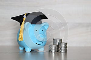 Graduation hat on piggy bank with stack of coins money on wooden background, Saving money for education concept