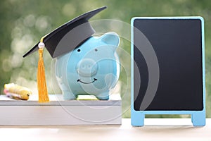 Graduation hat on piggy and stack of coins money on natural green background, Saving money for education concept