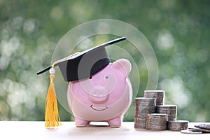 Graduation hat on piggy and stack of coins money on natural green background, Saving money for education concept