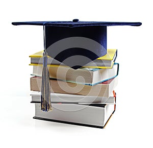 Graduation hat and stack of books isolated on white