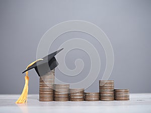 Graduation hat on stack of coins. The concept of saving money for education, student loan, scholarship, tuition fees