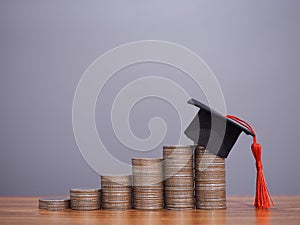 Graduation hat on stack of coins. The concept of saving money for education, student loan, scholarship, tuition fees in future