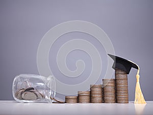 Graduation hat on stack of coins. The concept of saving money for education, student loan, scholarship, tuition fees in future