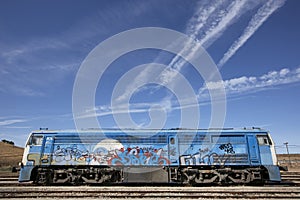 Graffiti on a train with railroad and blue sky.