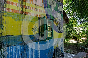 graffitied wall. Old courtyard wall in the forest. green wooden window on art painted wall