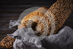 Grain bread in a basket with a napkin  on a dark  background, wheat loaf , close-up