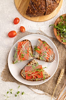 Grain bread sandwiches with red tomato cheese and microgreen on gray, top view, close up