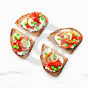 Grain bread slices for sandwiches with curd cheese, baked capsicum, green fresh peas and mint on a light background. Top