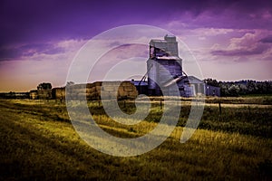 Grain elevator in countryside with hay bails photo