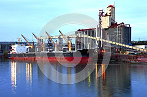 Grain elevators & cargo ship at dusk.