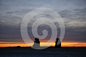 Grain elevators silhouetted against a winter sunset