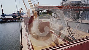 Grain loading to bulker ship cargo container at sea grain terminal in seaport. Grain shipment from silos to bulk vessel