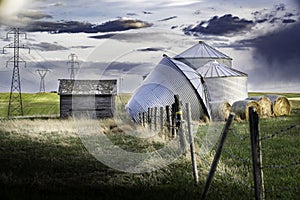 Grain Silos folded over after a severe thunder storm with barbed wire fence posts