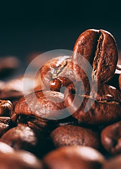 Grains of black coffee on a black granite countertop with yellow light from behind.