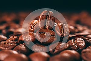 Grains of black coffee on a black granite countertop with yellow light from behind. Advertising photo of coffee.