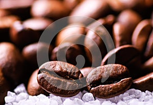 Grains of black coffee on sugar granules