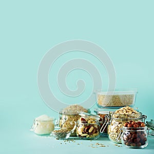 Grains, cereals, nut, dry fruits in glass jars over blue background with copy space. Clean eating, healthy, vegan diet concept