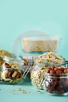 Grains, cereals, nut, dry fruits in glass jars over blue background with copy space. Clean eating, healthy, vegan diet concept