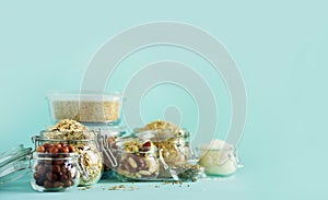 Grains, cereals, nut, dry fruits in glass jars over blue background with copy space. Clean eating, healthy, vegan diet concept