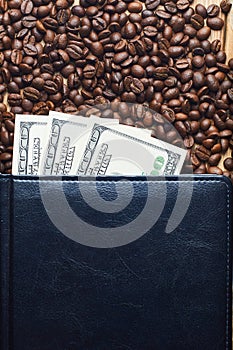 Grains of coffee and money in a leather notebook. Coffee business.