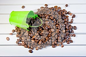 Grains of coffee are poured from a green decorative bucket