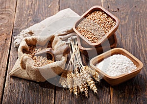 Grains, flour and wheat ears on a wooden table