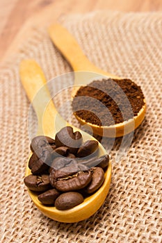 Grains and ground coffee with wooden spoon on jute canvas