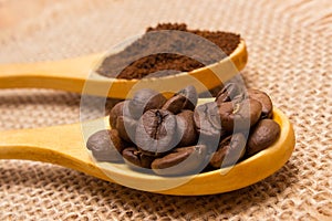 Grains and ground coffee with wooden spoon on jute canvas