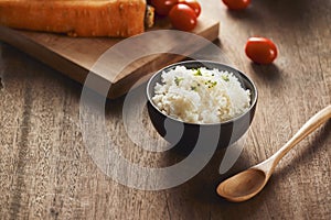 Grains of rice in a wooden bowl and ingredients for a vegetarian recipe - healthy eating concept