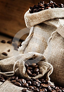 Grains of roasted coffee in bags on old wooden table in rustic s