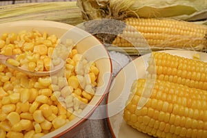 Grains of sweet corn in a plate and ears of corn on the wood table. Healthy diet. Fitness diet. For a sweet treat. Close up
