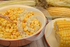 Grains of sweet corn in a plate and ears of corn on the wood table. Healthy diet. Fitness diet. For a sweet treat. Close up