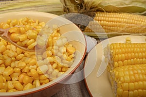 Grains of sweet corn in a plate and ears of corn on the wood table. Healthy diet. Fitness diet. For a sweet treat. Close up