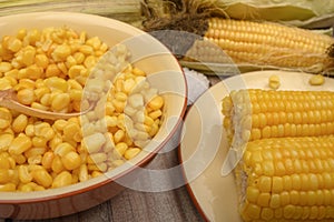 Grains of sweet corn in a plate and ears of corn on the wood table. Healthy diet. Fitness diet. For a sweet treat. Close up