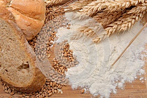 Grains, wheat ears, flour, bread and bagel on a wooden table. Co