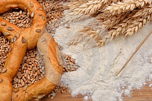 Grains, wheat ears, flour and pretzel on a wooden table. Concept