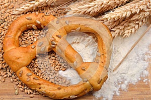 Grains, wheat ears, flour and pretzel on a wooden table. Concept