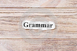 Grammarof the word on paper. concept. Words of Grammar on a wooden background