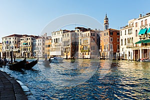 Grand canal, gondolas and pleasure boat. Campanile of Church of Santi Apostoli